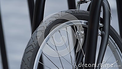 Closeup front bicycle wheel standing on shared parking. Alternative transport. Stock Photo