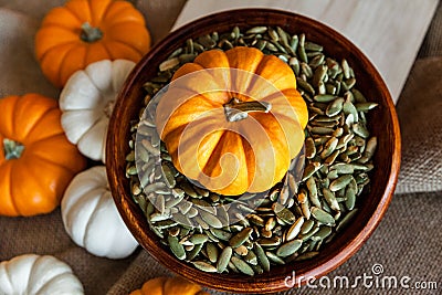 Closeup of Full Bowl of Peeled Pumpkin Seeds with Orange Pumpkin, Autumn Holidays Stock Photo