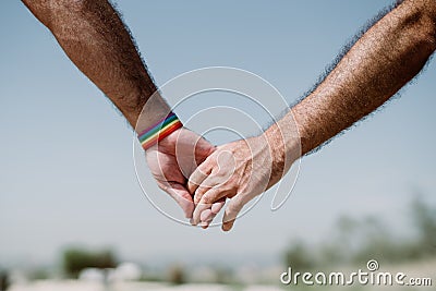 closeup of a gay couple holding hands, Rainbow flag is a symbol of lesbian, gay, bisexual, and transgender. LGTB,LGBT Stock Photo