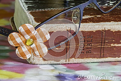 Closeup of girls glasses with pretty flower resting on bible, co Stock Photo