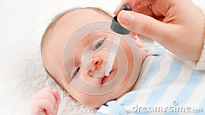 Closeup of giving vaccine from eyedropper or syringe to newborn baby boy Stock Photo