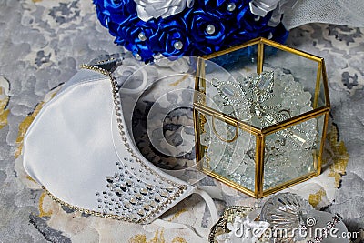 Closeup of a glass box with sparkling jewelry for wedding and a facial mask Stock Photo