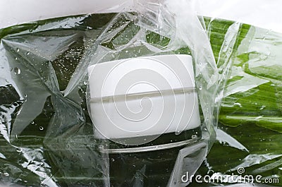 Closeup of glass container of cream on the green fresh leaf under the plastic wrapping material.Branding moke up Stock Photo