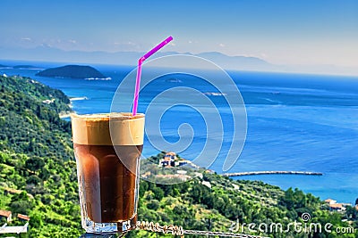 Closeup of a glass of iced coffee on background of a beautiful view of the Aegean sea Stock Photo