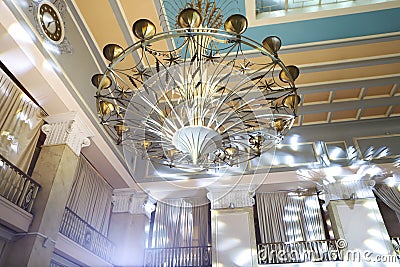 Closeup of gorgeous gold metal chandelier with stars and ears of wheat. Palace ceiling with beautiful lighting Stock Photo