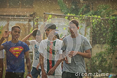 Closeup group of teenagers walks by under tropical rain on dominican city street Editorial Stock Photo