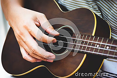 Closeup of guitarist hand playing guitar. Musical instrument concept. Outdoors and Leisure theme. Selective focus on left hand. Stock Photo