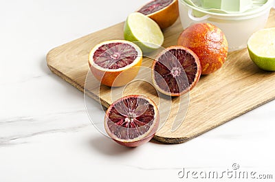 Closeup of half blood oranges and lime on the cutting board, manual juicer.Preparation of fresh tasty juice Stock Photo