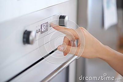 Closeup, hand and button on oven for cooking in kitchen for heating, preparation and appliance. Person, press and switch Stock Photo