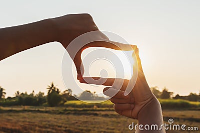 closeup hand framing view distant over sunset. business concept Stock Photo