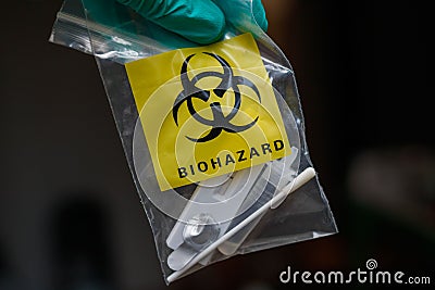 Closeup of a hand in a glove holding a self-test of Covid 19 in a plastic biohazard bag Stock Photo