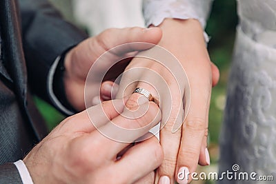 Close-up of the hand of the groom puts a wedding ring on the brides finger, the ceremony on the street, selective focus Stock Photo