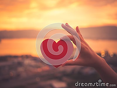 Closeup hand holding red heart during sunset background. Stock Photo