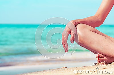 Closeup hand and leg of woman sit on sand beach at seaside. Happy young Asian woman relax and enjoy holiday at tropical paradise Stock Photo