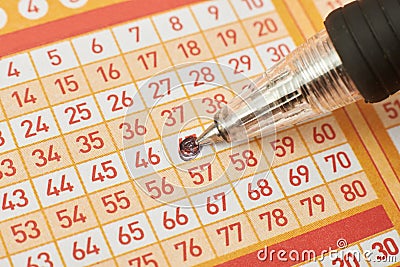Closeup of hand marking number on lottery ticket with pen. Stock Photo