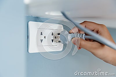 Closeup hand plug in wall socket electricity to power electric appliance Stock Photo