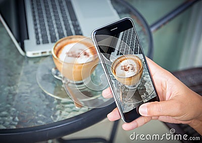 Closeup hand taking photo coffee on work table Stock Photo