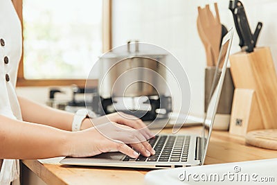 Closeup hand using laptop computer in kitchen for learning cook food or find menu recipe from internet. home technology concept Stock Photo