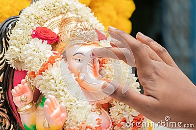 Closeup of hands applying Tilak or Kumkum to Lord Ganesha during Indian religious ganesha or vinayaka Chaturthi festival ceremony Stock Photo