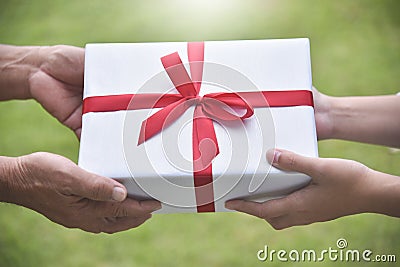 Closeup on hands Asian woman giving a white gift box to elderly man. Stock Photo
