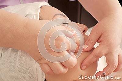 Closeup of the hands of the beautician do massage of the chin to the woman. The masseur presses his fingers on the female face. Stock Photo