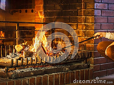 Closeup hands with fire iron poker at fireplace. Stock Photo