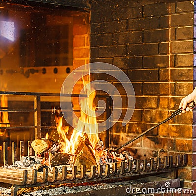 Closeup hands with fire iron poker at fireplace. Stock Photo