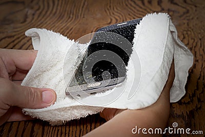 Closeup Hands holding White cloth with wet smart phone drops on wooden floor Stock Photo