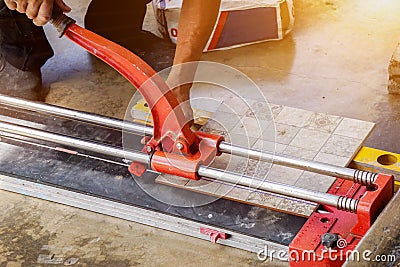 Closeup hands of laborer using cutting tile machine at construction site Stock Photo