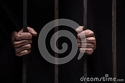 Closeup on hands of man sitting in jail. Stock Photo