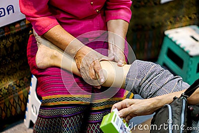 Hands of massager lady are demonstration touch and massage a tourists leg in Thailand culture fair Stock Photo