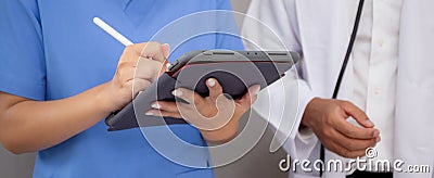 Closeup hands nurse writing report medical and health care on tablet while specialist doctor explaining and check. Stock Photo