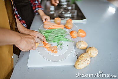 Closeup of hands slicing carrots on chopping board Stock Photo