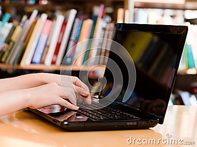 Closeup hands typing on notebook in library Stock Photo