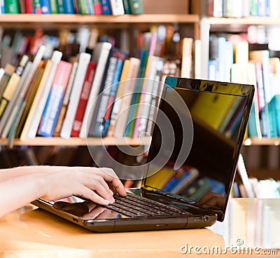 Closeup hands typing on notebook in library Stock Photo