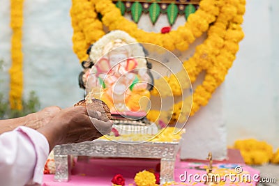 Closeup of Hands worshiping lord ganesh by offering aarti during vinayaka Chaturthi festival pooja or puja celebration at home in Stock Photo