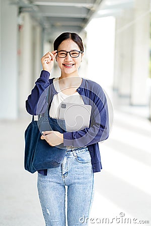 Closeup happiness cheerful Asian young female student in casual cloth holding a laptop with touch eyeglas Stock Photo