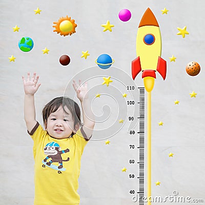 Closeup happy asian kid stand for measure height with cute cartoon at the marble stone wall textured background in growth of kid c Stock Photo
