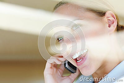 Closeup of a happy female speaking on the cellphone. View through a glass - Happy young female speaking on the cellphone Stock Photo