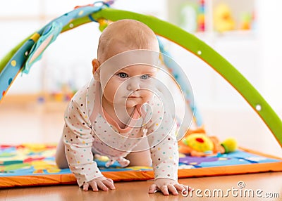 Closeup of happy seven months baby girl crawling on colorful playmat Stock Photo