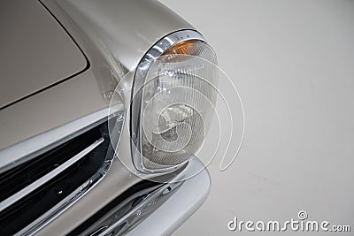 Closeup of the headlight of a silver vintage car under the lights isolated on a grey background Stock Photo