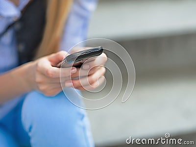 Closeup on hipster girl writing sms while sitting on stairs Stock Photo