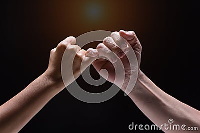 Closeup human hand ,Hook each other`s little finger,on black background,blurry light around Stock Photo