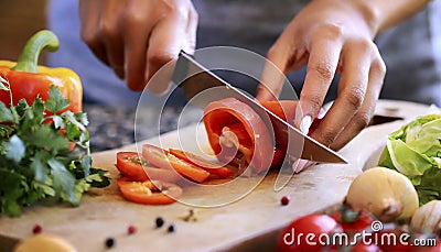 Closeup on human hands cutting vegetables on wooden cutting board with knife Stock Photo