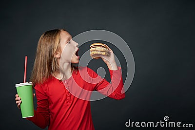 Closeup of hungry little girl looking forward to bite a hamburger Stock Photo