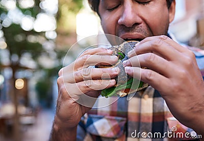 Hungry man sitting outside eating a delicious poppy seed bagel Stock Photo