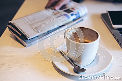 Closeup image of coffee cup , newspaper , laptop and smart phone on wooden table Stock Photo