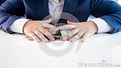 Closeup image of greedy businessman grabbing and holding lots of money on office desk Stock Photo