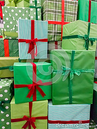 Closeup image of pile of lots of Christmas gifts. Stack of green boxes with red ribbons with New Year presents Stock Photo