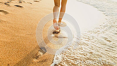 Closeup image of sexy barefoot female feet walking on the wet sand and calm warm waves at sea beach Stock Photo
